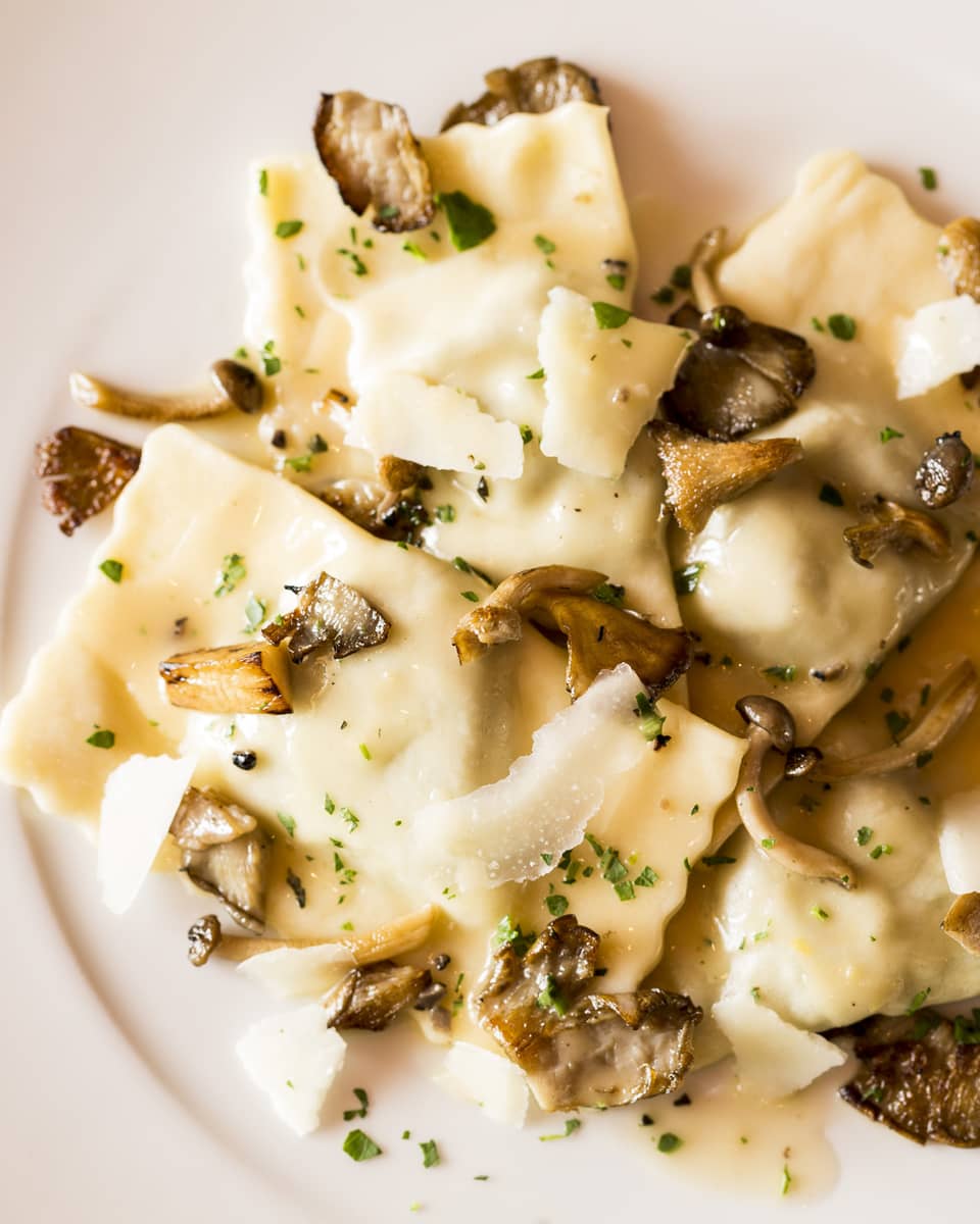 Veal Ravioli pasta garnished with shaved parmesan cheese, mushrooms on plate