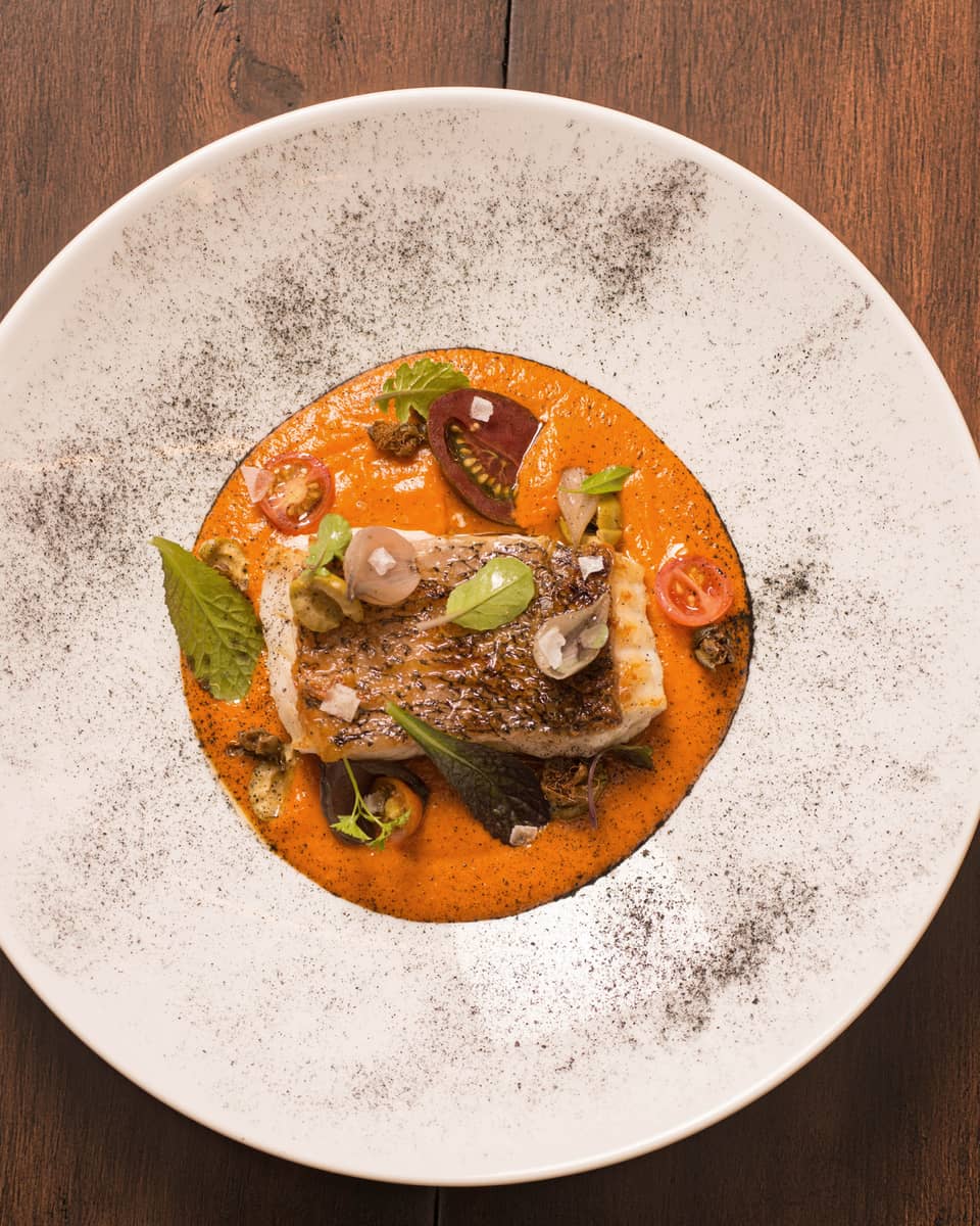 Tomato risotto topped with a piece of grilled fish