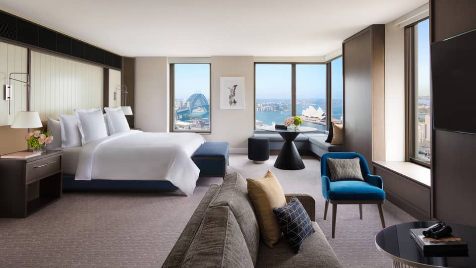 A cozy bedroom with subtle bursts of colourful decor, overlooking the iconic Sydney Harbour