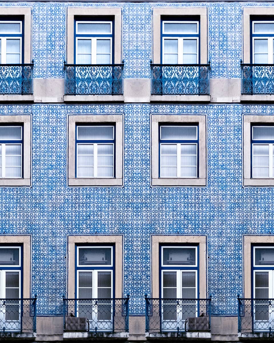 A blue tiled wall with many windows and balconies.