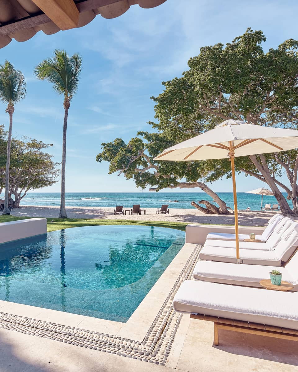 Arena Beach House Puerto Vallarta, Mexcio. Private pool with row of lounge chairs, umbrella, palm trees, ocean view