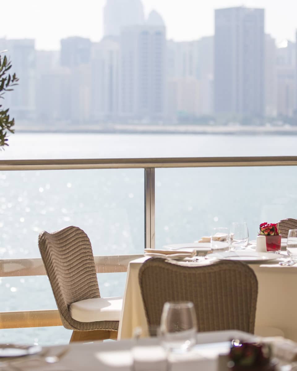 A four seasons staff setting an indoor Cafe Milano table overlooking the water