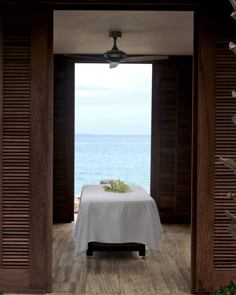 Massage table with white sheet under outdoor pavilion with wood shutters