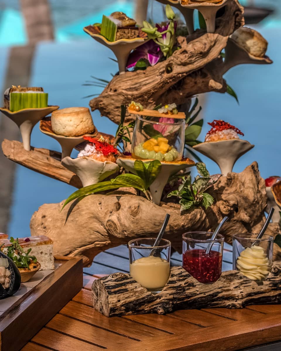 Afternoon tea spread with sweets and savouries presented on a piece of driftwood